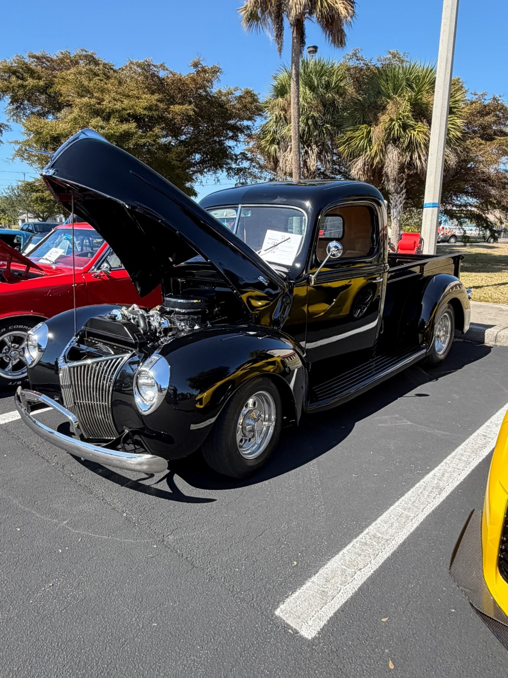Shiny black classic pickup truck with its hood open, showing the engine